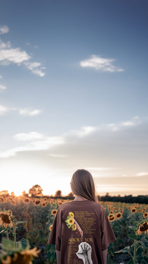 Person standing in a sunflower field with a clear sky